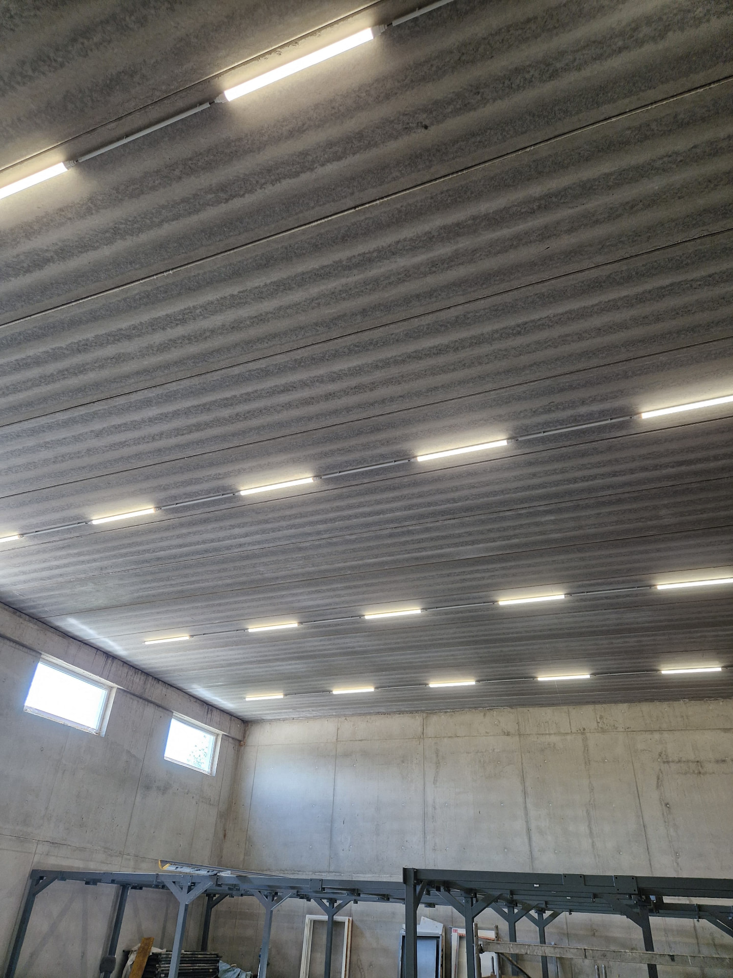 Stropné LED svietidlá v rade pod betónovým stropom skladovej haly